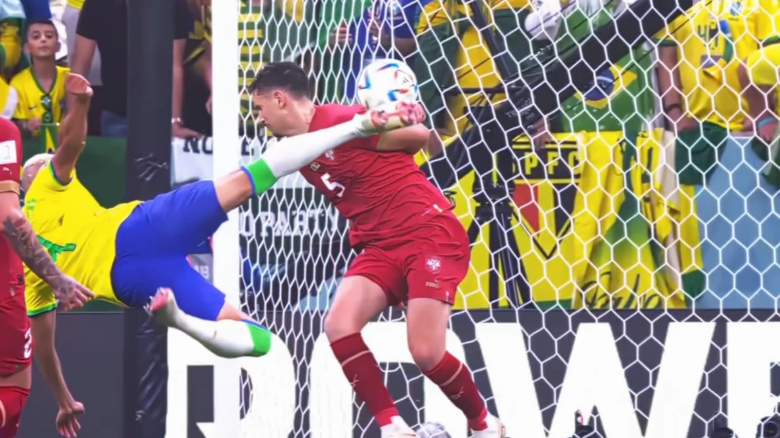 A player in Brazil colours mid bicycle-kick as a defender in red clears the ball in front of a packed goal